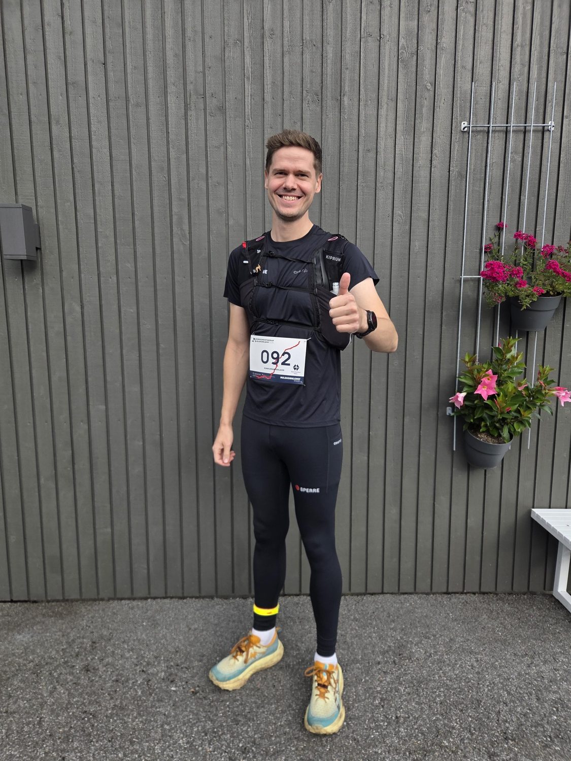 Magnus med startnummer 092, løpevest og tights, tommel opp foran en grå vegg.
