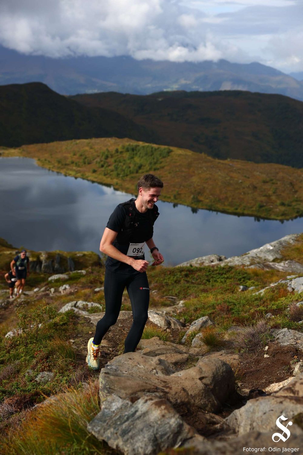 Magnus på stien over tregrensa, med vann og fjell bak.