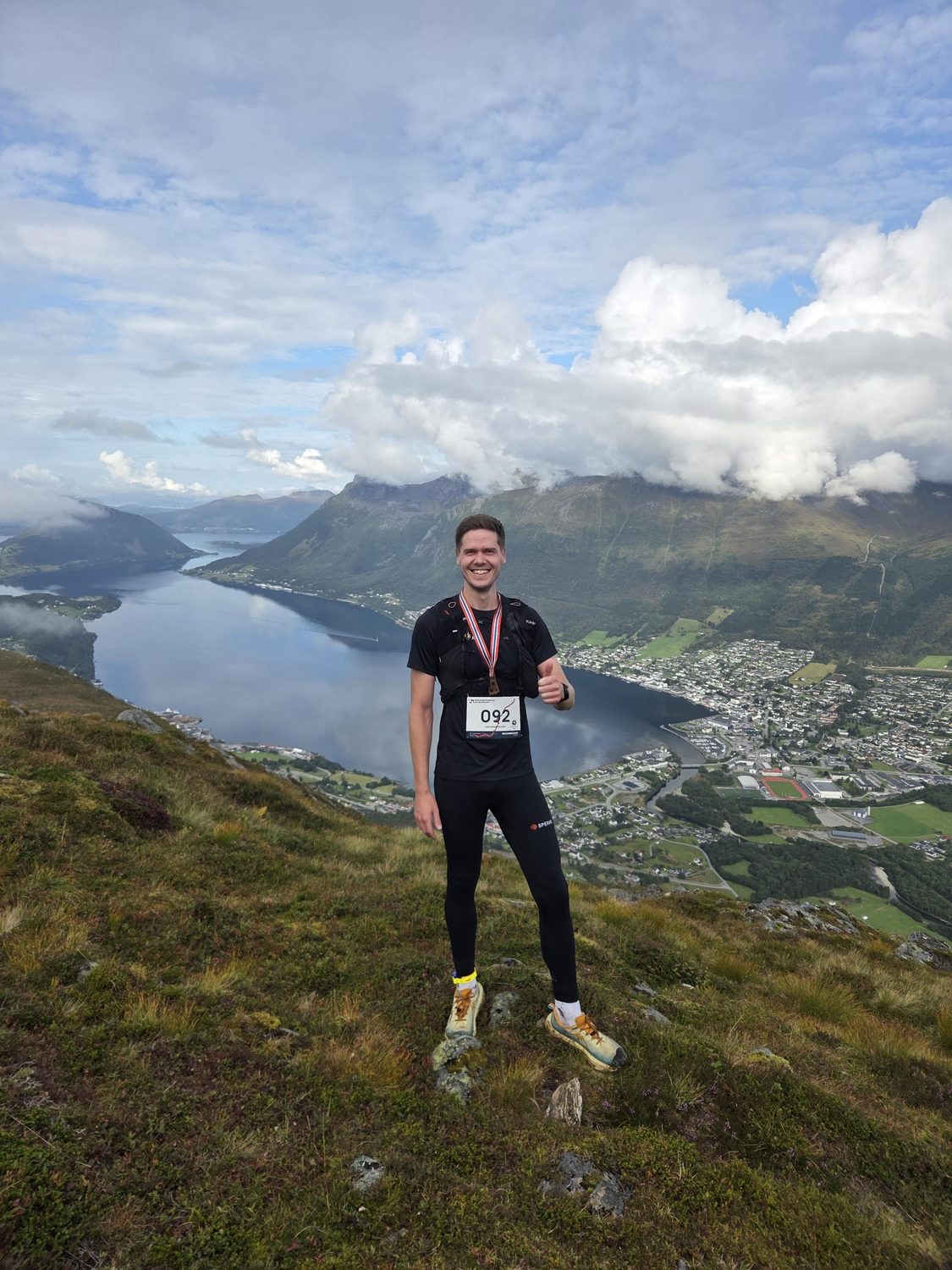Magnus på toppen av Melshornet med medalje, utsikt over Voldsfjorden og Volda sentrum.